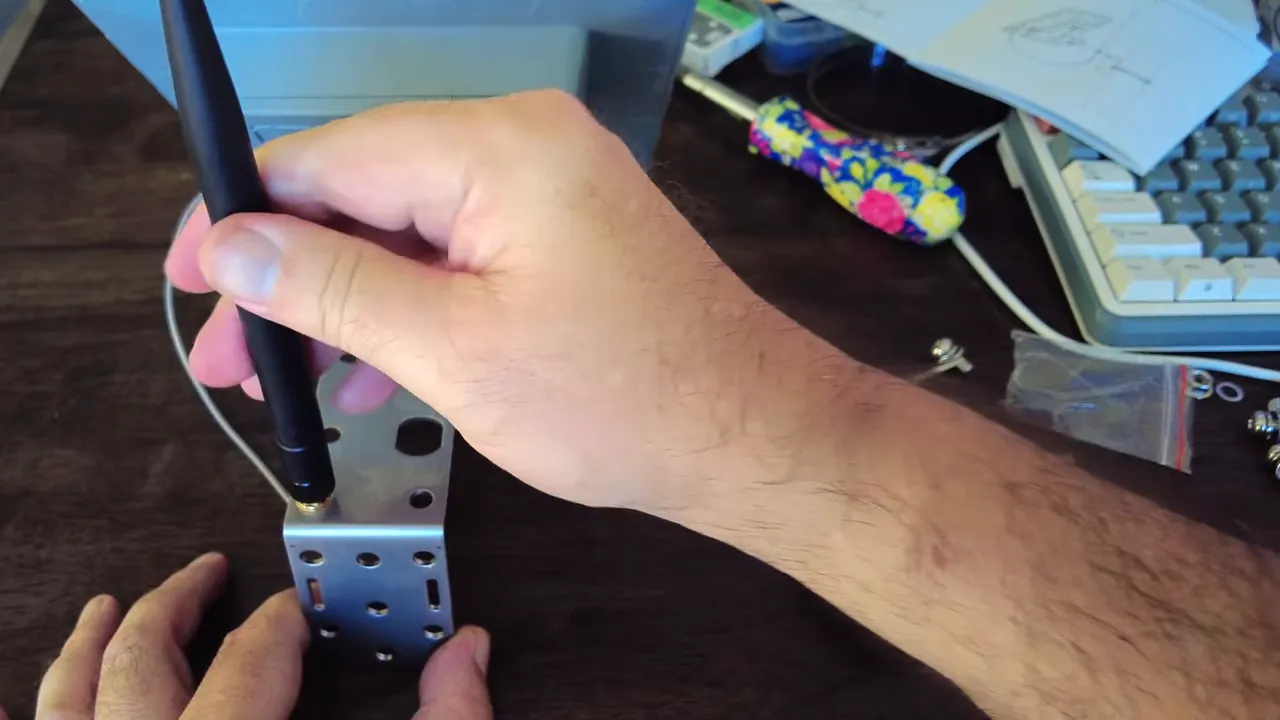 Hand attaching a 2 dBi antenna to the metal mounting bracket