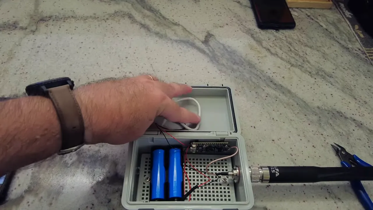 open waterproof enclosure with coiled solar cable, batteries, Heltec board and antenna attached
