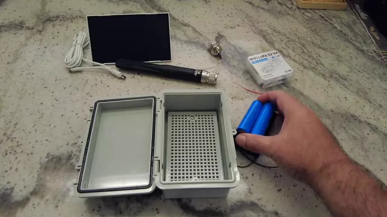 Open waterproof enclosure on a workbench with a Type N connector, antenna, solar panel and 18650 batteries laid out for assembly.