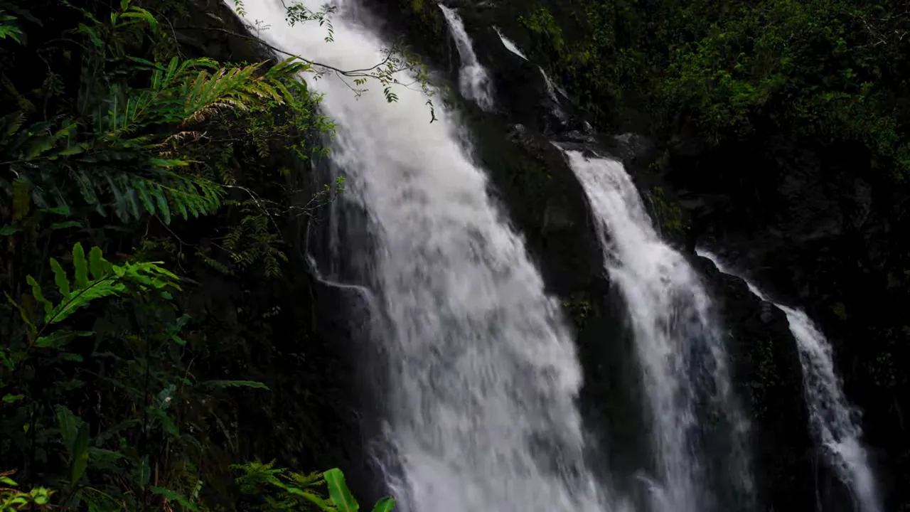 Detailed view of rushing water over the falls with dark volcanic rock background