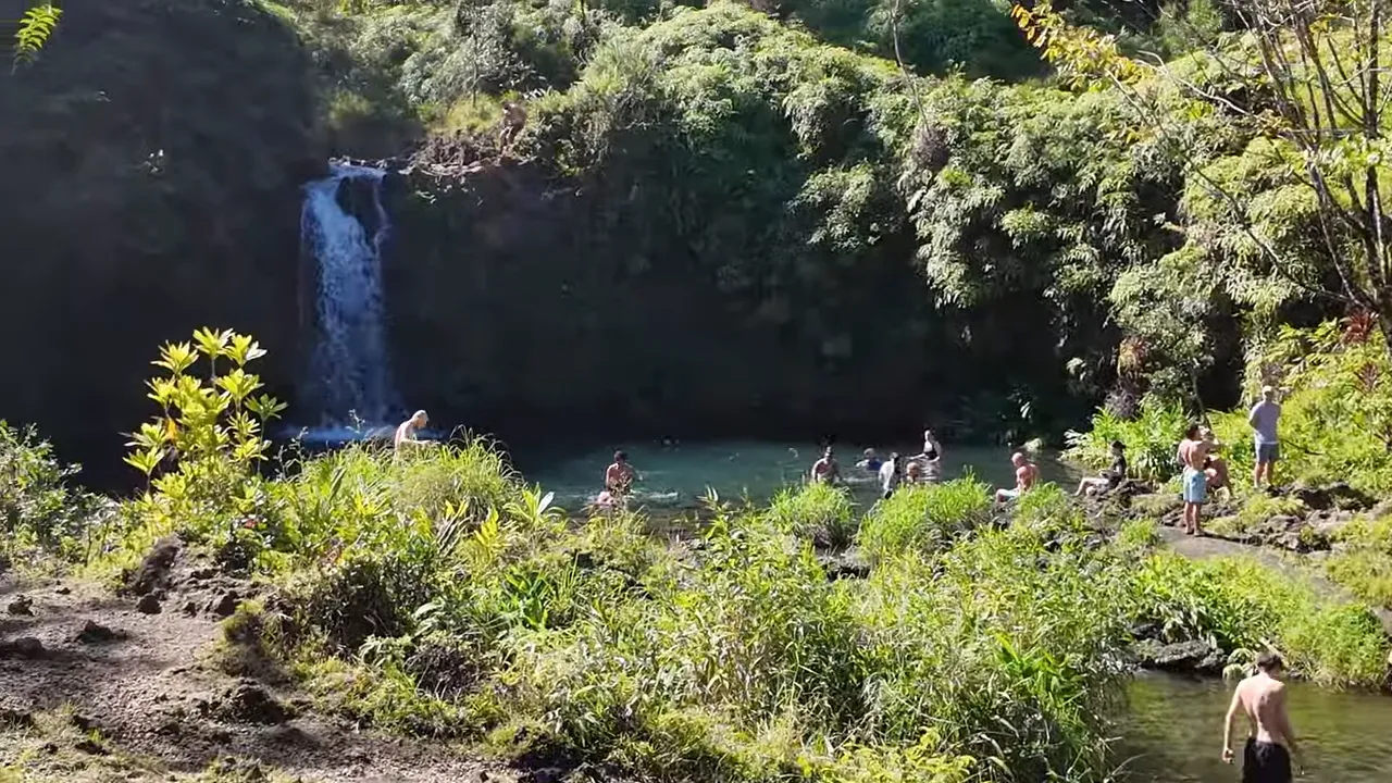 Wide view of a waterfall and swimming pool surrounded by vegetation at Puaʻa Kaʻa State Park