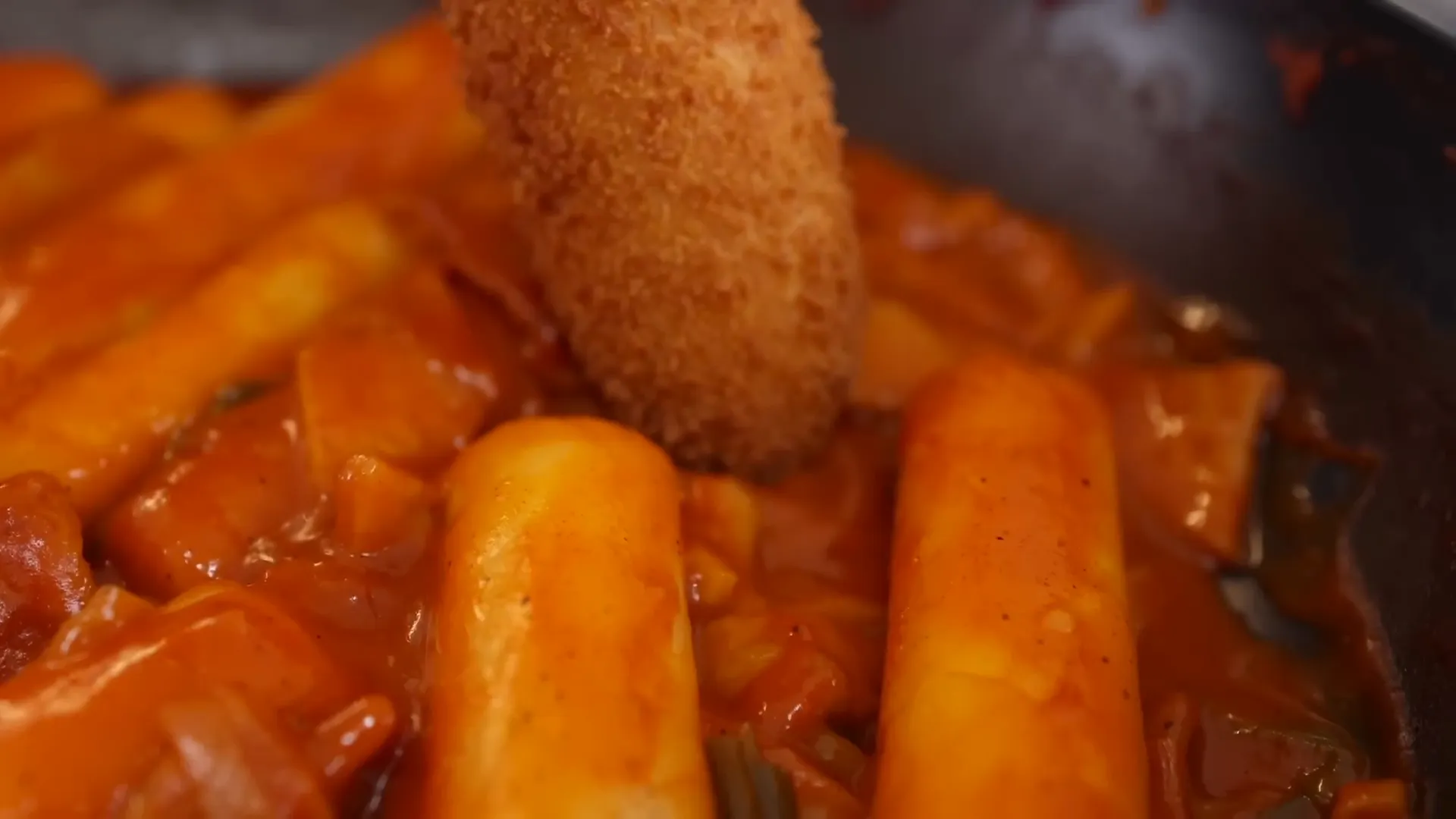 Dipping a Korean style corn dog in Tteokbokki sauce