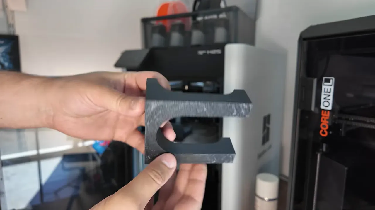black wall-mounted garden tool holder shown in hands over a wooden table