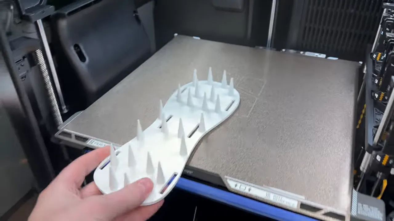 white lawn aerator sole with printed spikes held above a printer bed