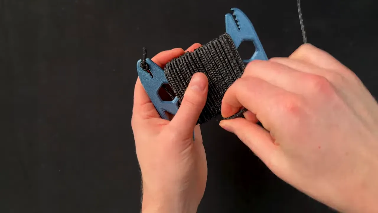 Blue printed paracord holder holding a tightly wound bundle of black paracord