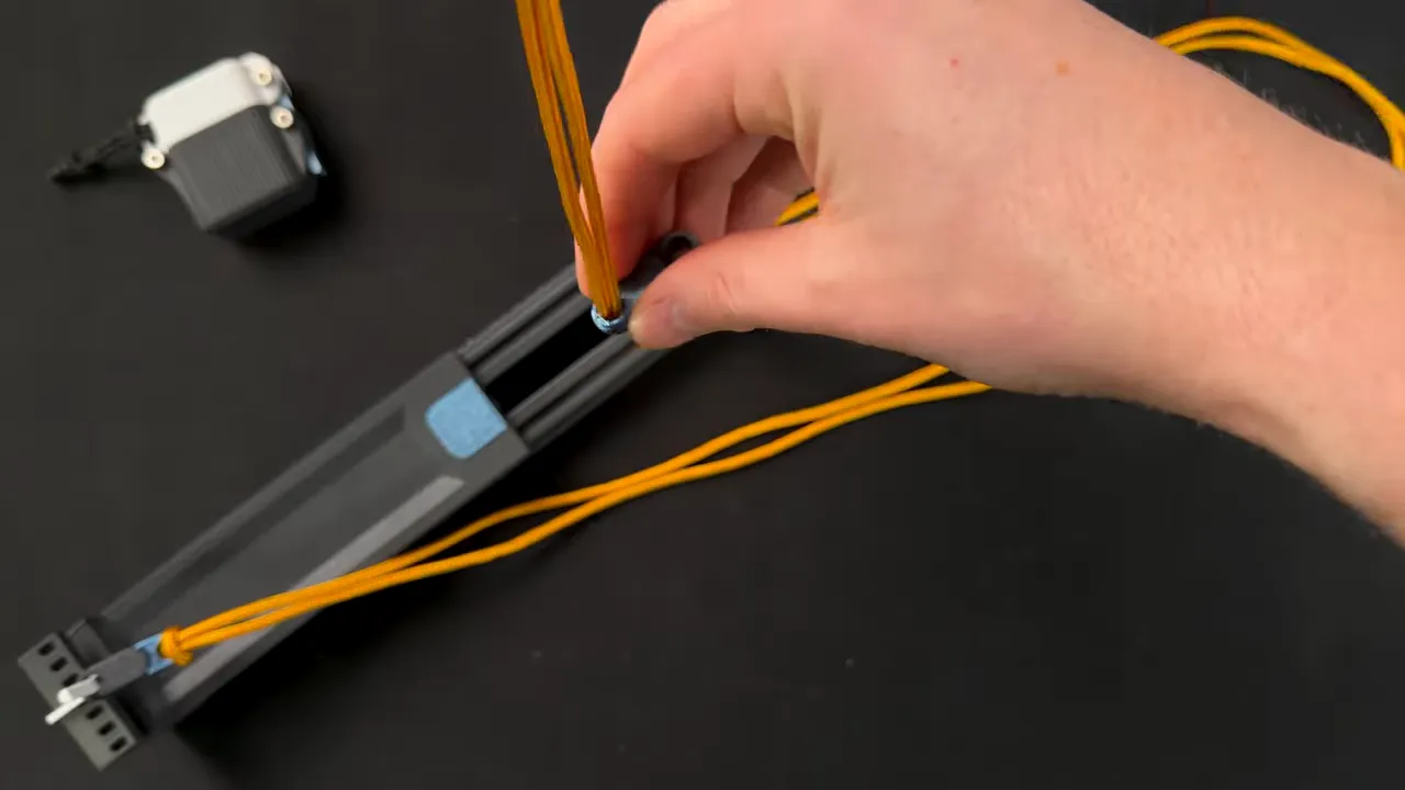 Hand securing orange paracord into a printed holder for organization