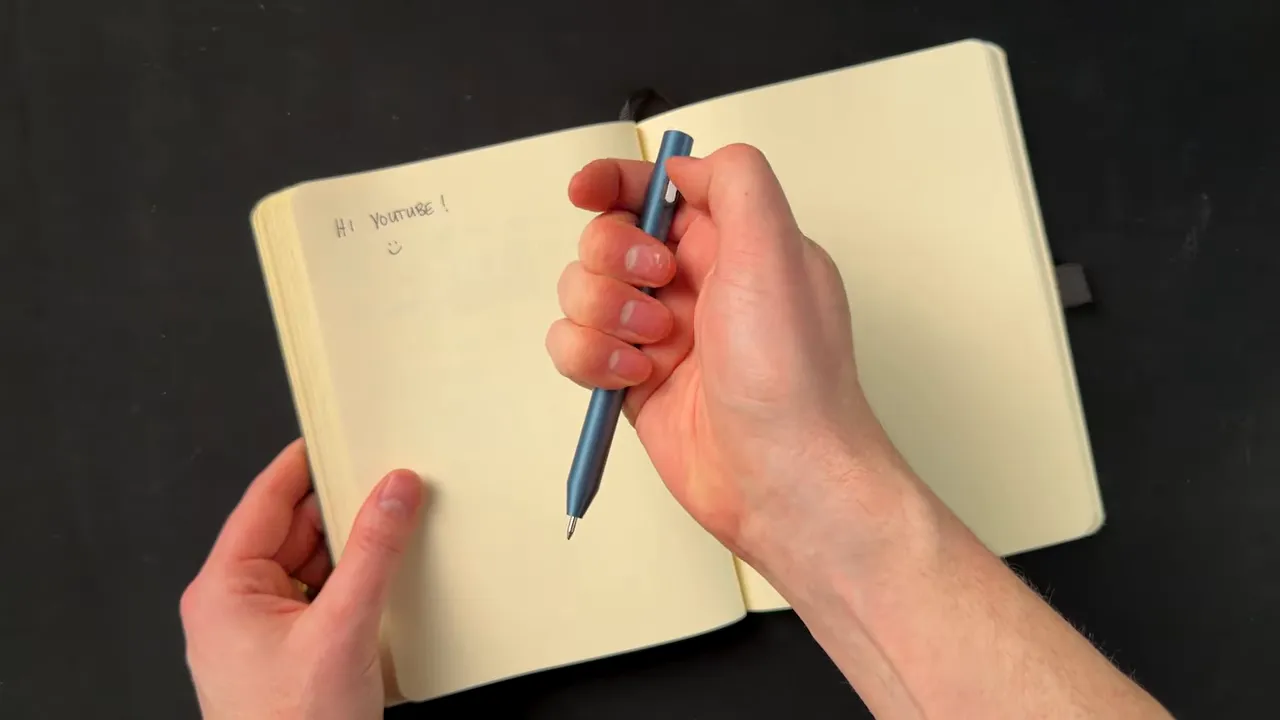 Hands holding a 3D printed bolt-action pen over an open notebook