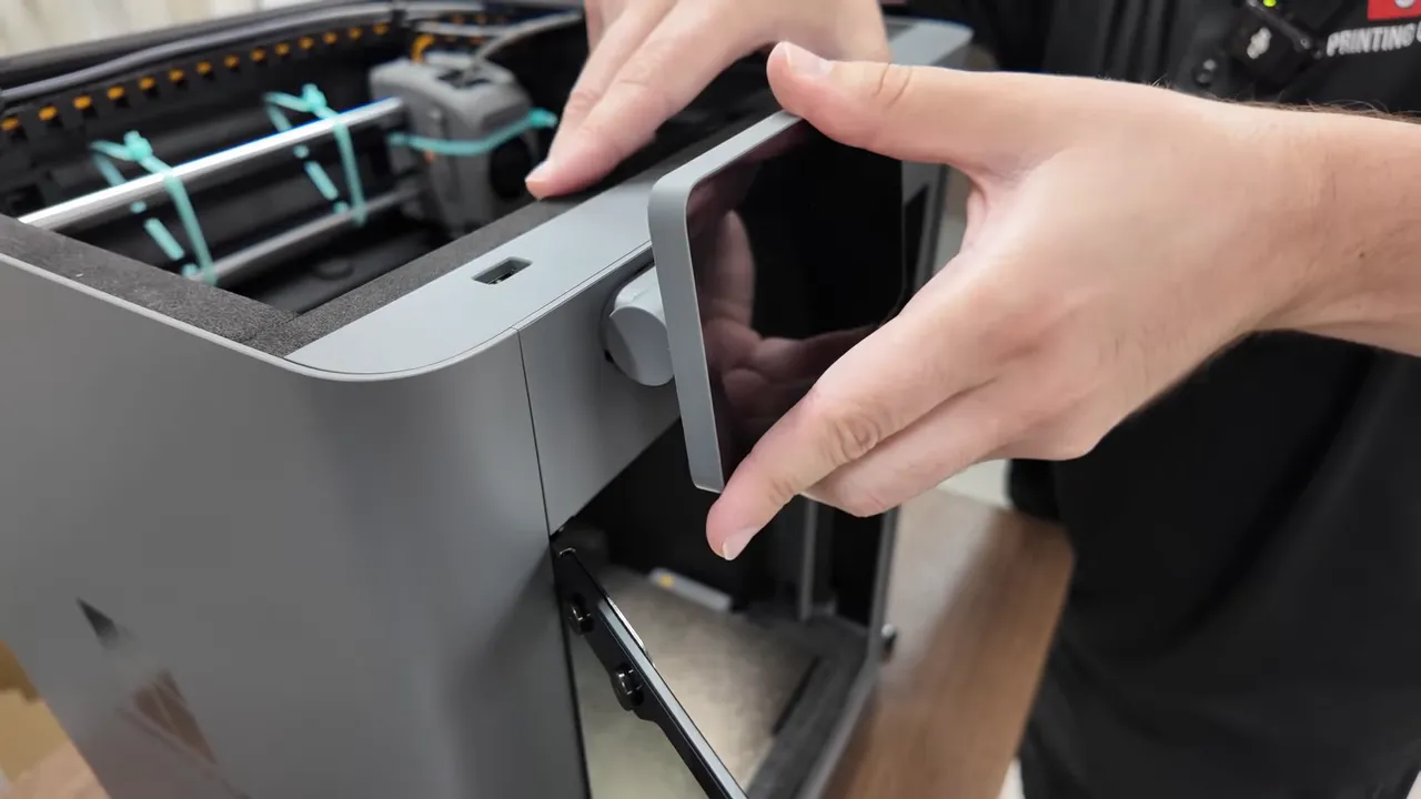 Hands aligning and pressing the BAMBU P2S touchscreen onto its mounting knob