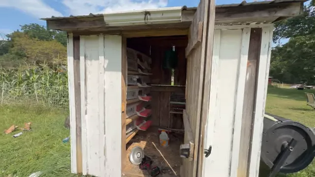 Small white-painted coop with open wooden door and stacked quail cages inside
