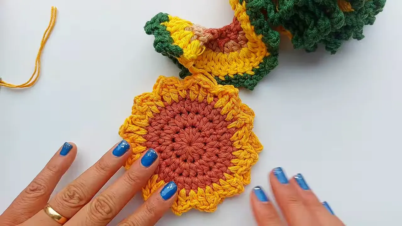 Finished brown and yellow crochet sunflower hanging below a green and yellow spiral