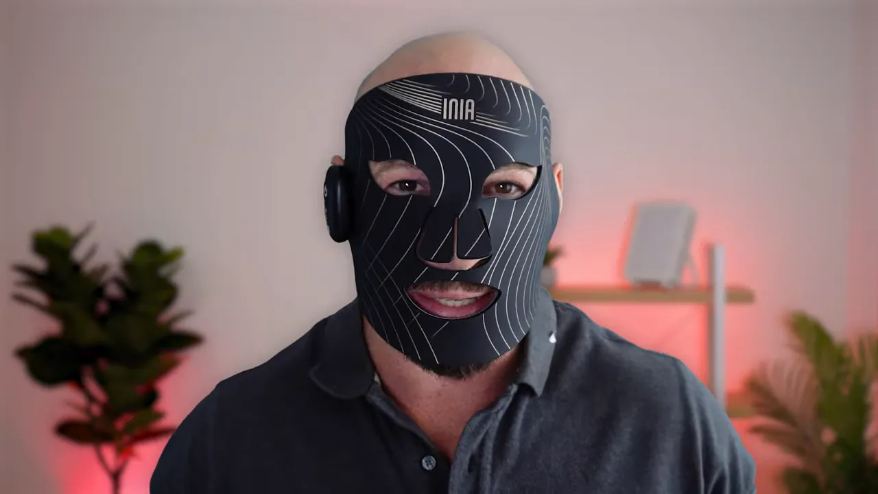 Front view of Inia Glow LED face mask worn, showing logo, mouth opening and controller on the side