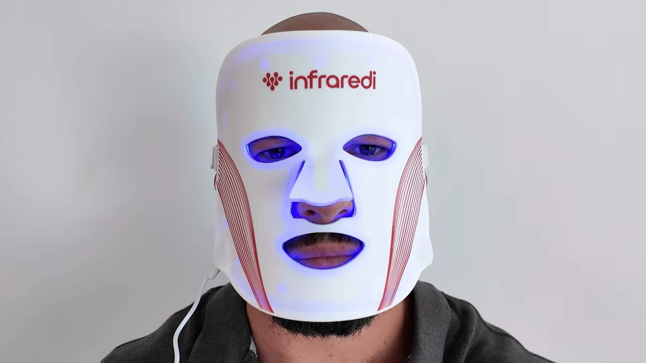 person wearing an Infredi LED face mask lit blue to demonstrate fit and build