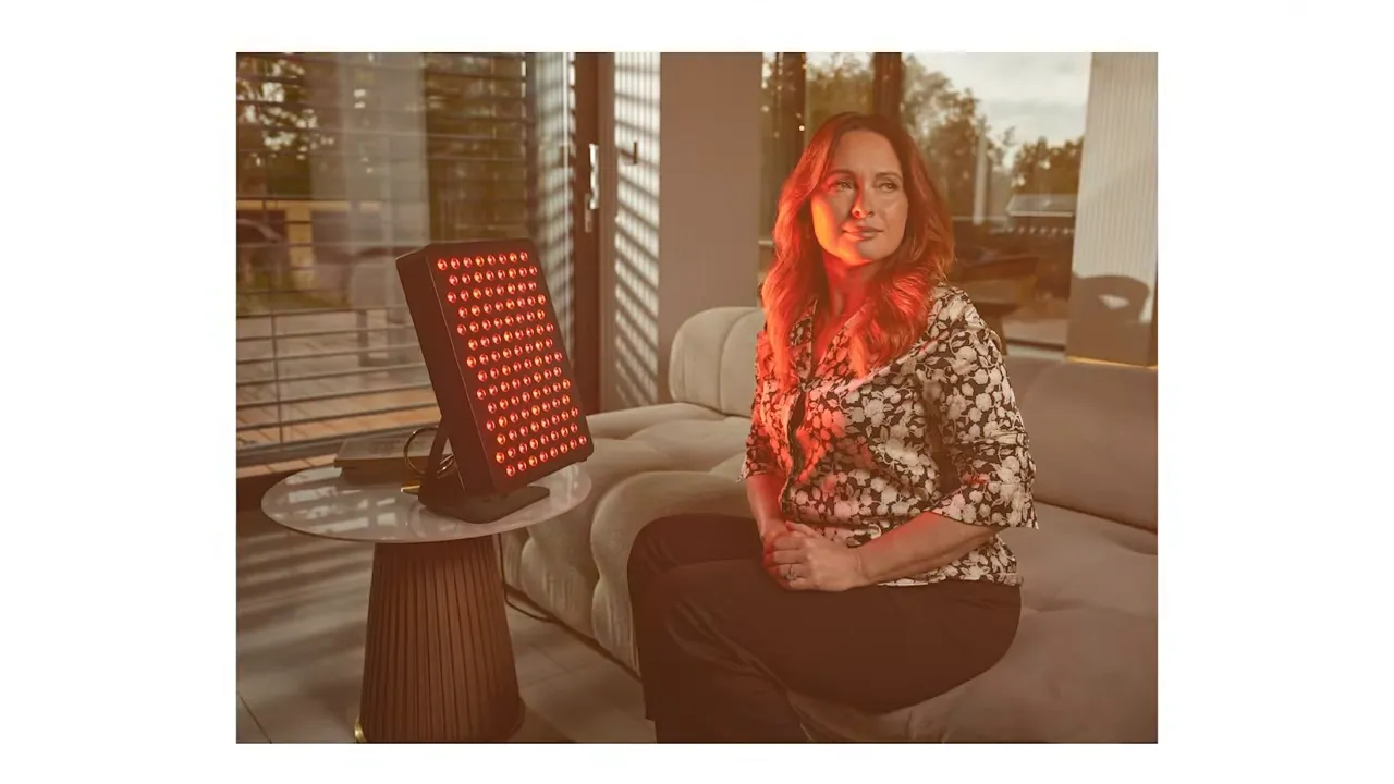 Large LED red light therapy panel on a side table next to a seated user in a living room