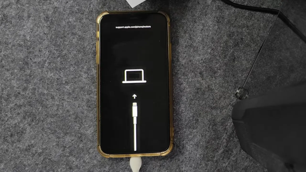 iPhone affichant l écran de mode Recovery avec un câble et un ordinateur