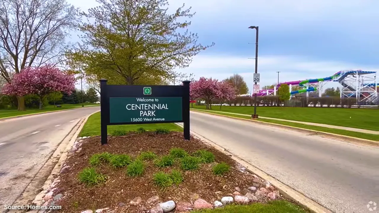Centennial Park sign beside a road with trees and recreation structures