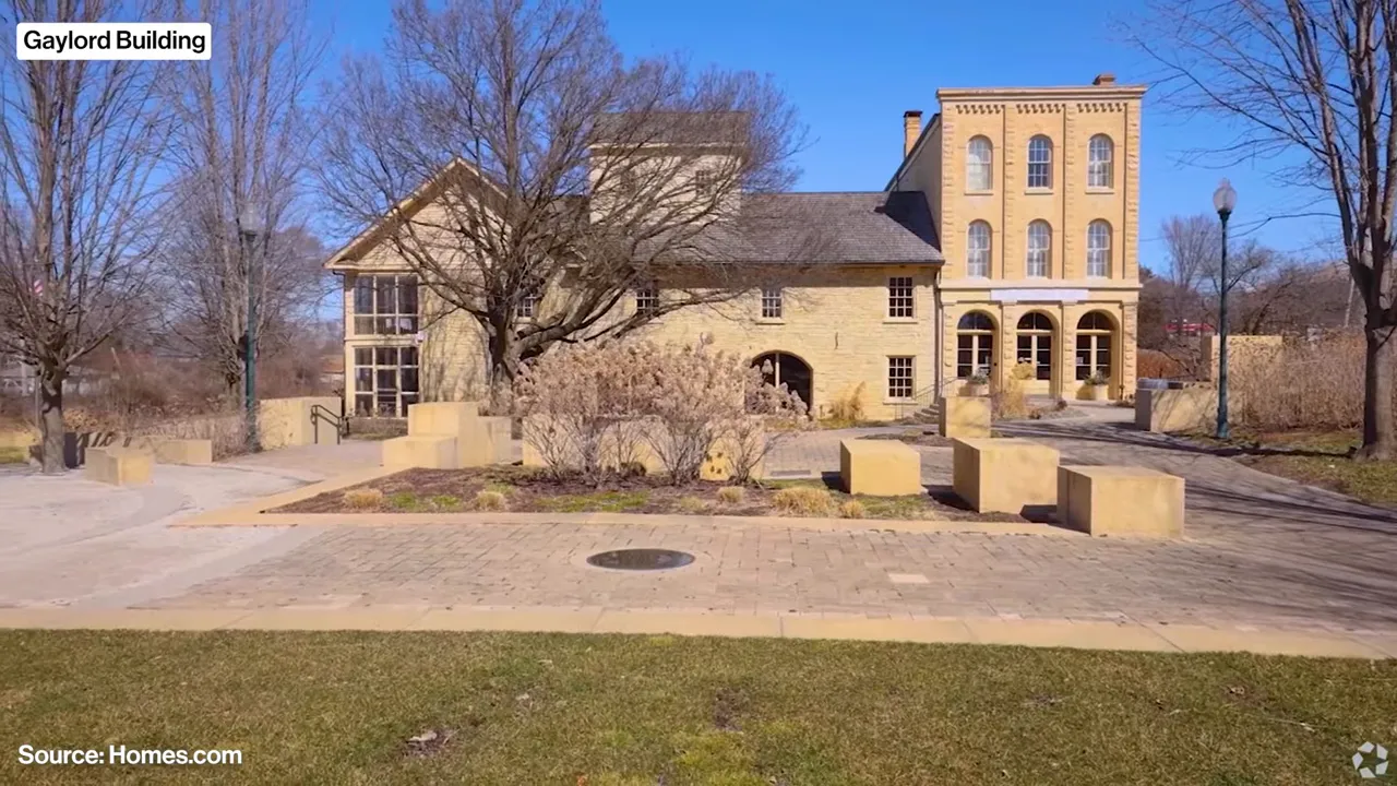 Historic limestone Gaylord Building with a paved plaza and leafless trees