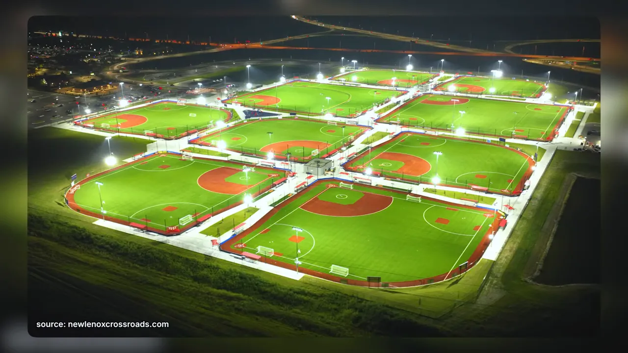 Aerial nighttime view of multiple illuminated baseball and softball fields