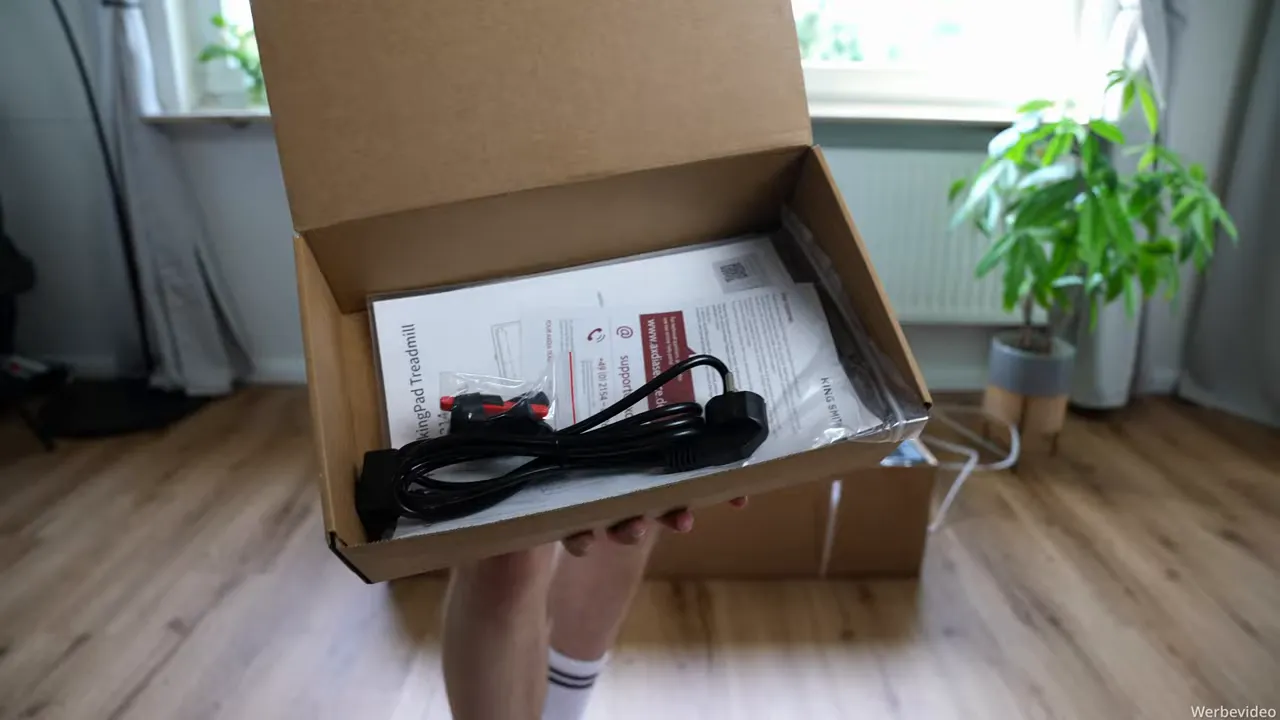 Geöffneter Karton mit Bedienungsanleitung und Netzkabel des WalkingPad X214