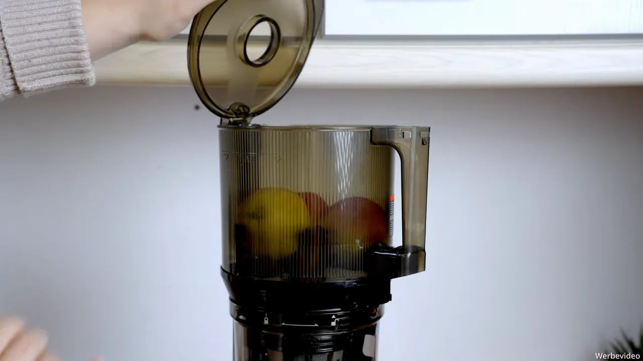 Drei Äpfel im geöffneten Hopper des Kuvings AUTO10S bereit zum Entsaften