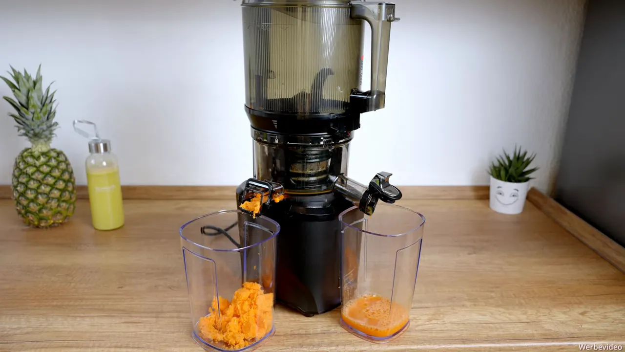 Kuvings AUTO10S mit Möhrentrester im Auffangbehälter und frisch gepresstem Karottensaft