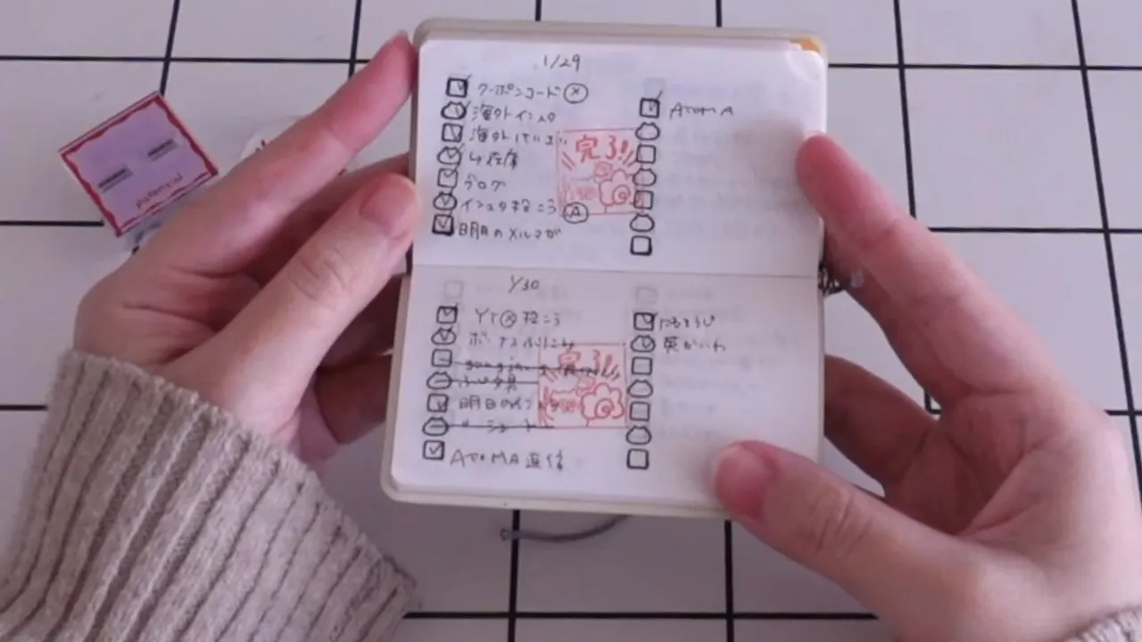 両面が開かれたミニメモに赤い「完了」スタンプが押されている手元写真（スタンプ本体が左に見える）