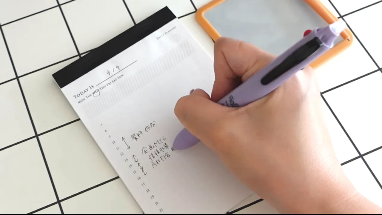 時間ごとの欄がある白いスケジュールパッドに予定を書く手元