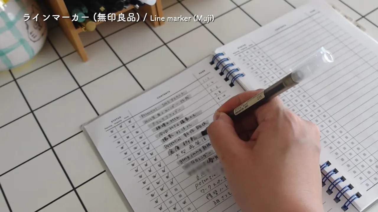 文字がたくさん書かれたノートの行をグレーのマーカーでなぞっている