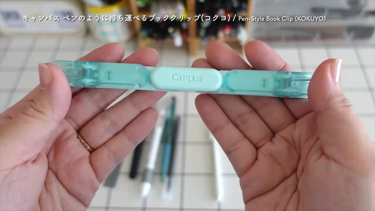 ミント色の細長いブッククリップを開いた状態で両手に持っている