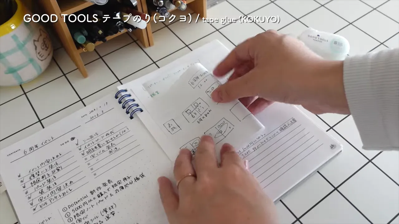 ノートの上に切り取った紙を貼り付けて手で押さえている