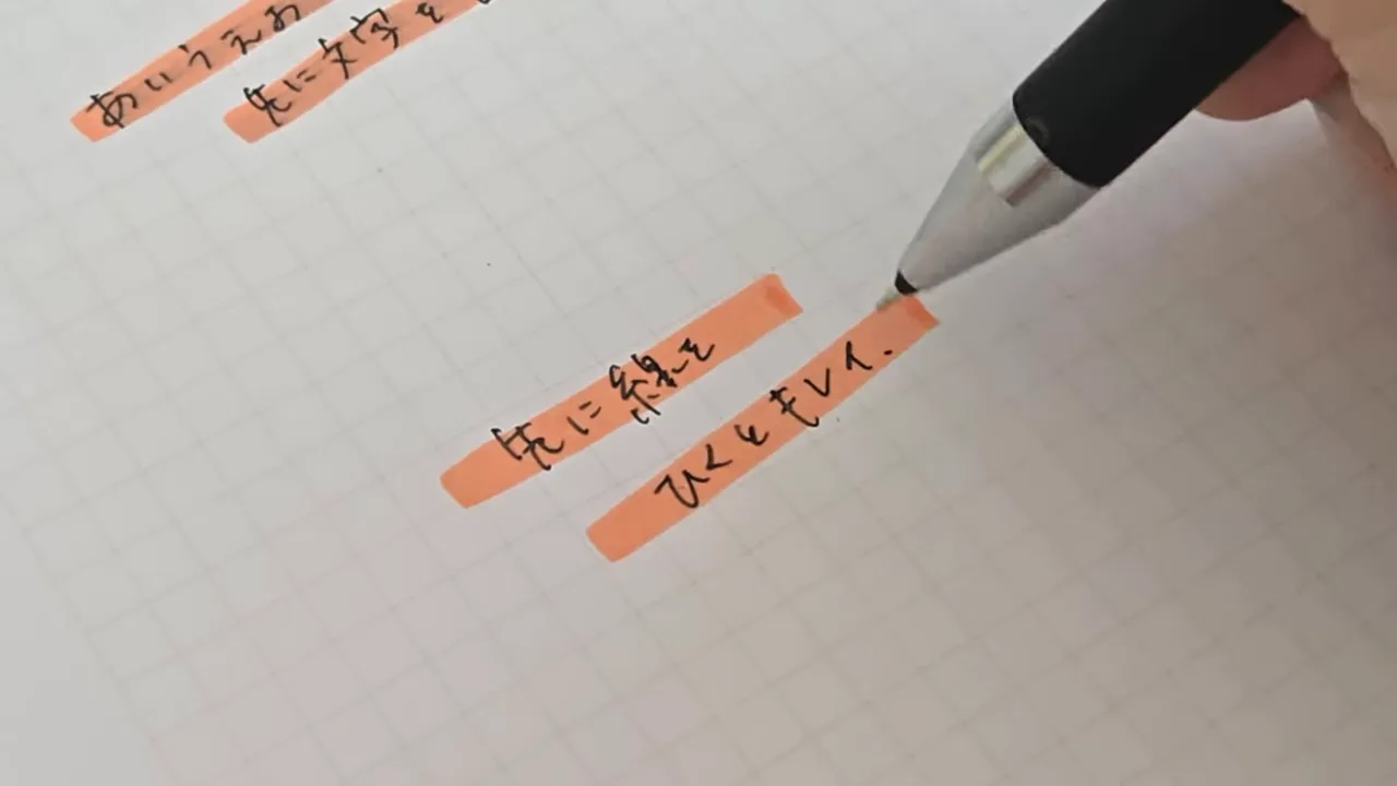 オレンジの蛍光ペンの線の上に黒い文字がにじまず書かれているノート