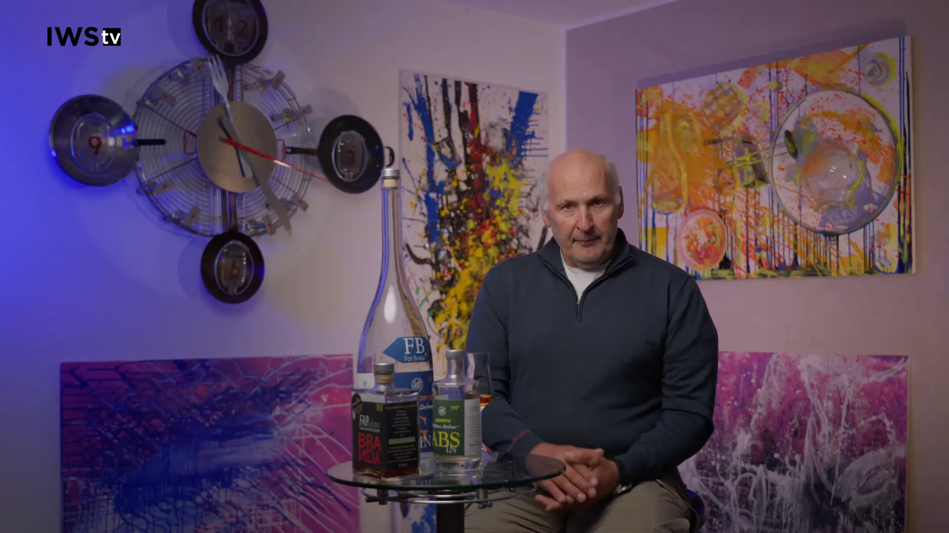 Tisch mit mehreren Cachaça‑Flaschen und einem Glas vor einem Interviewhintergrund