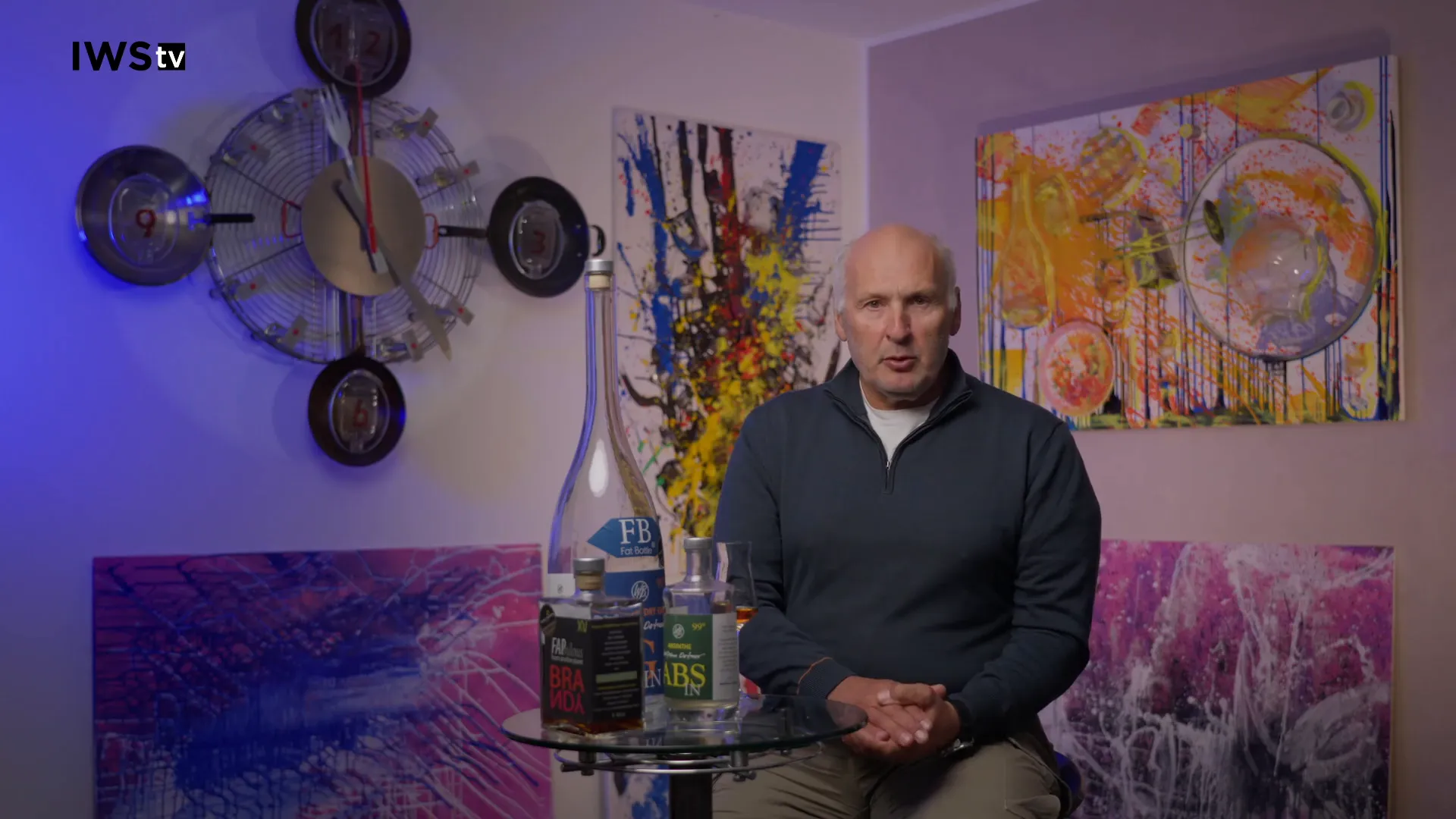 Tisch mit mehreren Cachaça‑Flaschen und Verkostungsglas vor dem Interviewgast