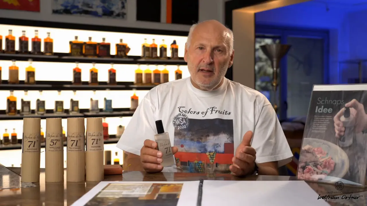 Presenter holding a Parfum de Vie distillate bottle up close with cardboard tube packaging and backlit sample bottles behind.