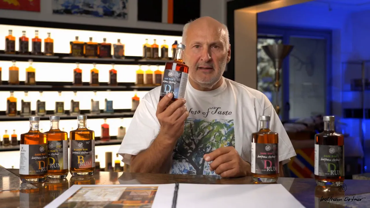 Presenter holding a ten-year rum bottle in front of a row of bottles on a table and backlit shelves of samples behind him.