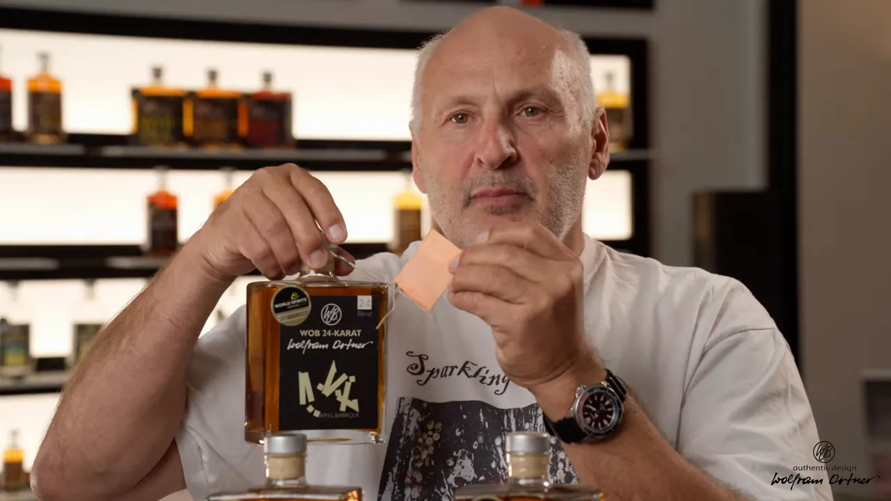 Nahaufnahme: WOB 24 Karat Flasche mit gravierbarem Anhänger, klar sichtbar vor Regal mit Flaschen