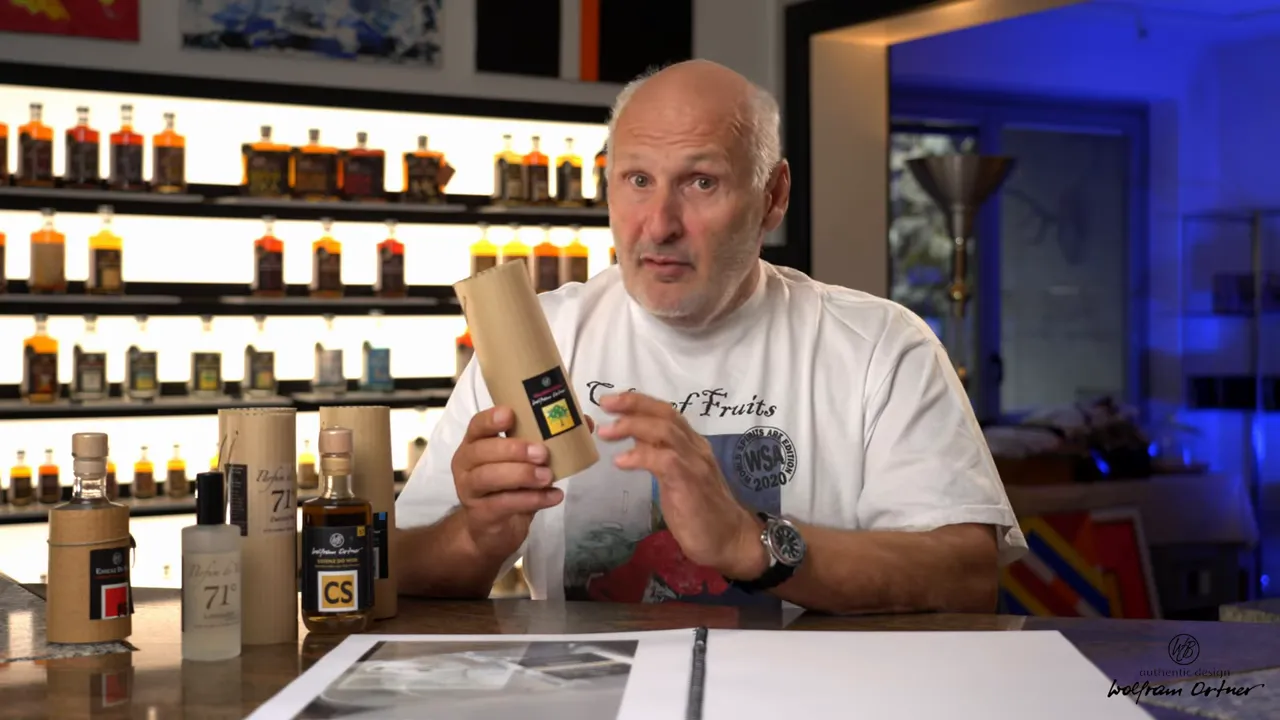 Moderator hält 71% Essenz in zylindrischer Papphülle, Produktetikett gut lesbar, Regal mit Flaschen im Hintergrund