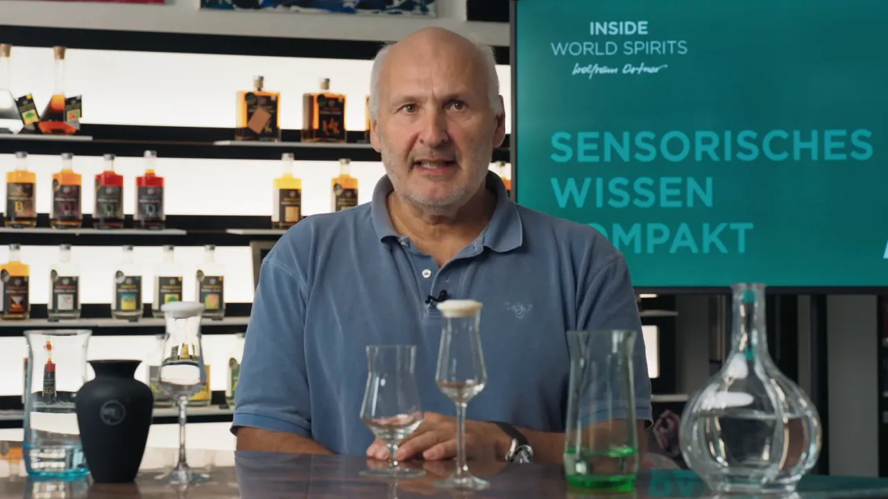 Tisch mit Nosing-Gläsern und Dekanter, Moderator im Hintergrund vor Schriftzug 'Sensorisches Wissen'