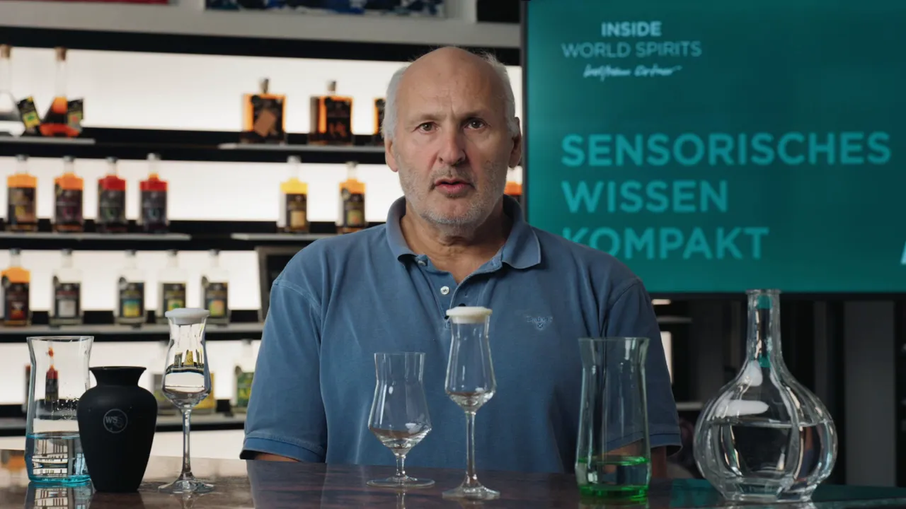 Tisch mit Dekanter, Probiergläsern und Glasstopfen vor einem Sprecher