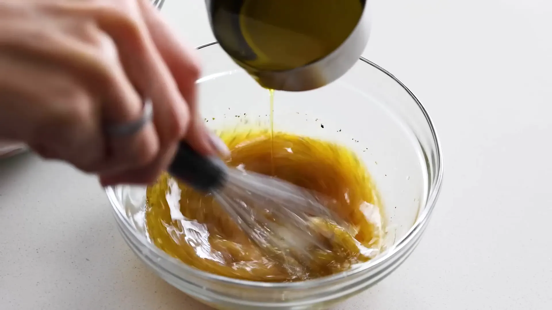Drizzling olive oil into the dressing