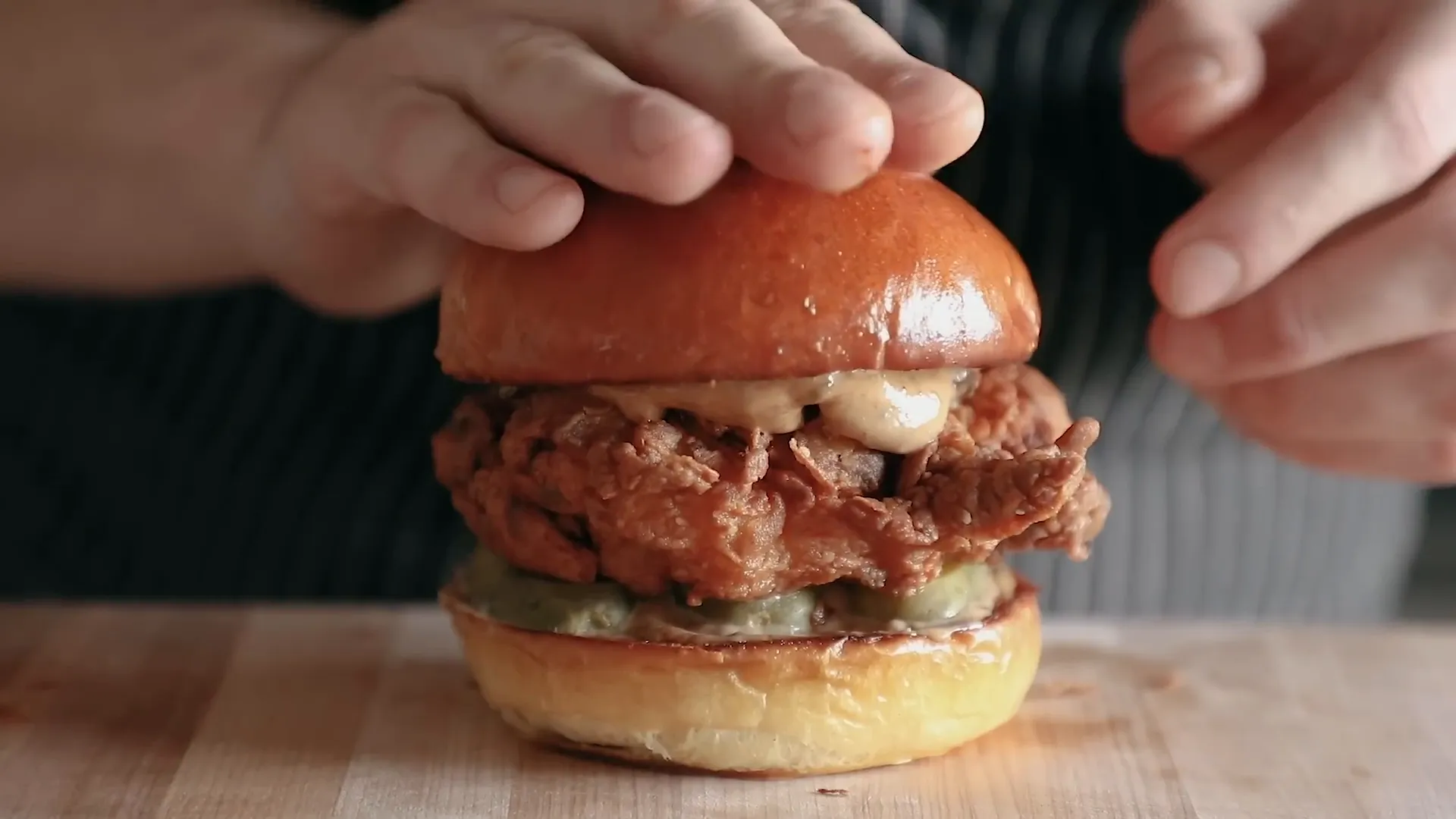 Assembled chicken sandwich with thick pickle planks and shiny milk bun