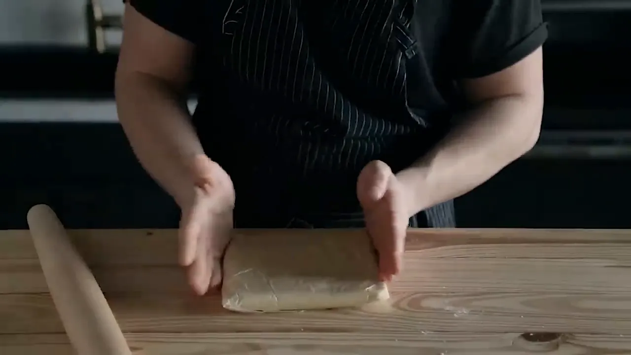 Rolling dough into a square shape on wax paper