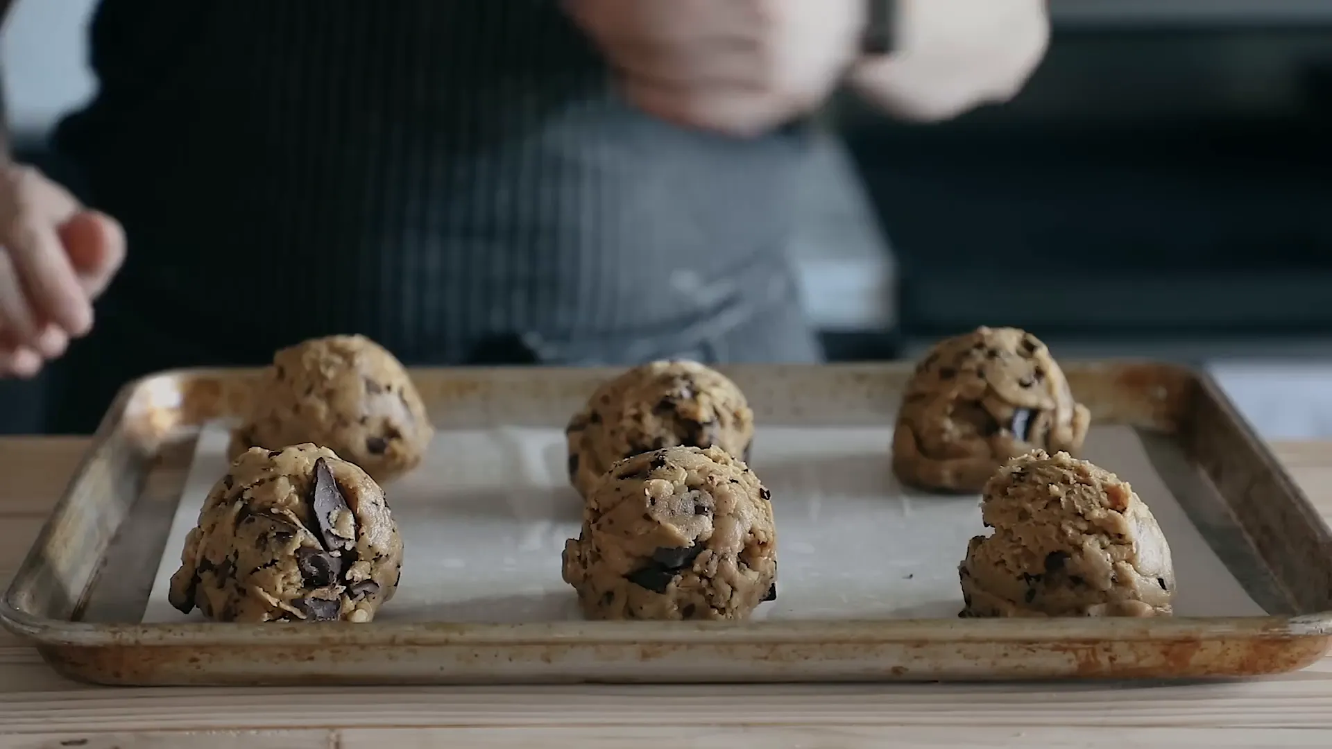 Six-ounce cookie dough balls arranged on parchment-lined baking sheet