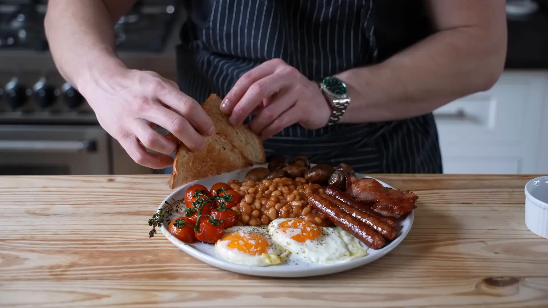 Full English breakfast with eggs, beans, bacon, sausages, tomatoes, and mushrooms