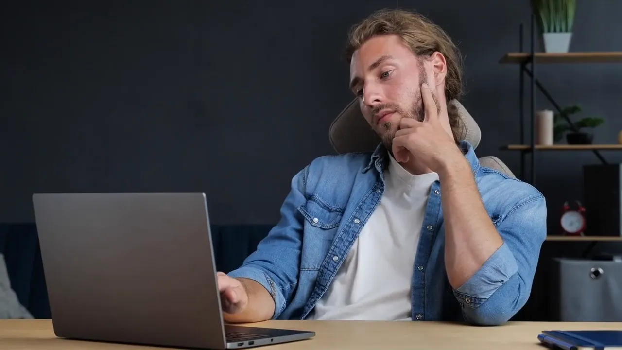 Mann prüft Laptop, wirkt unschlüssig – Symbol für Entscheidung und Pufferzeit