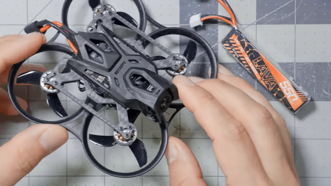 Top-down view of BetaFPV Pavo Pico II whoop with Lava 550mAh battery and hands for scale