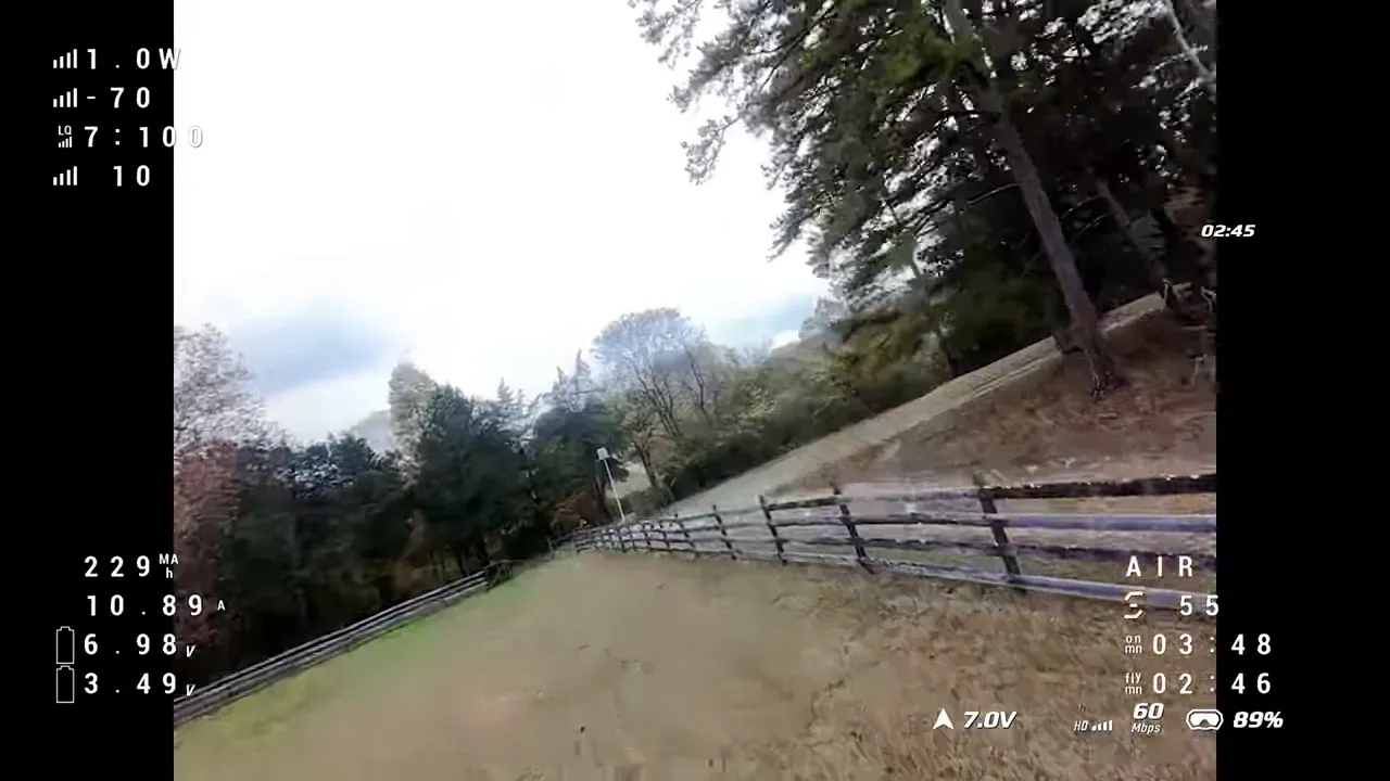 Pavo Pico II flying over a field and fence with on‑screen telemetry showing battery voltage and timers