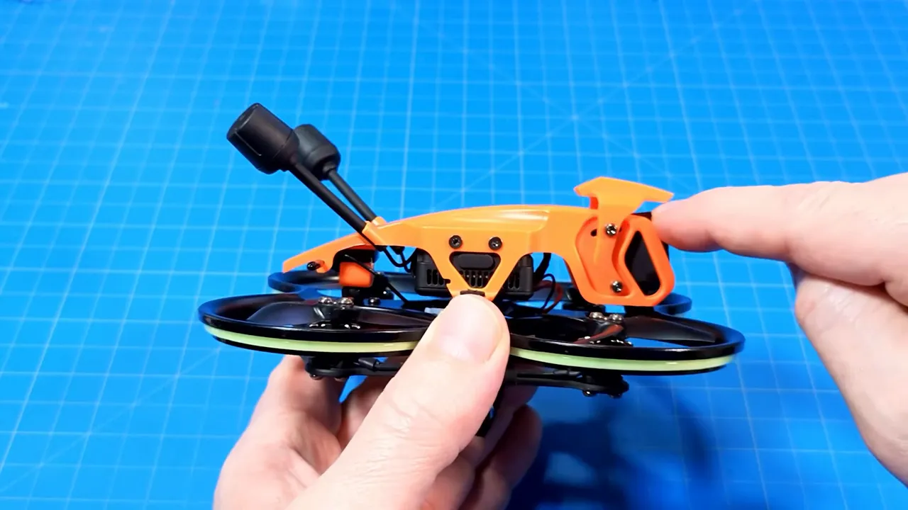 Close side view of the DarkStar22 orange canopy hood with a finger touching the hood and visible screws for camera tilt