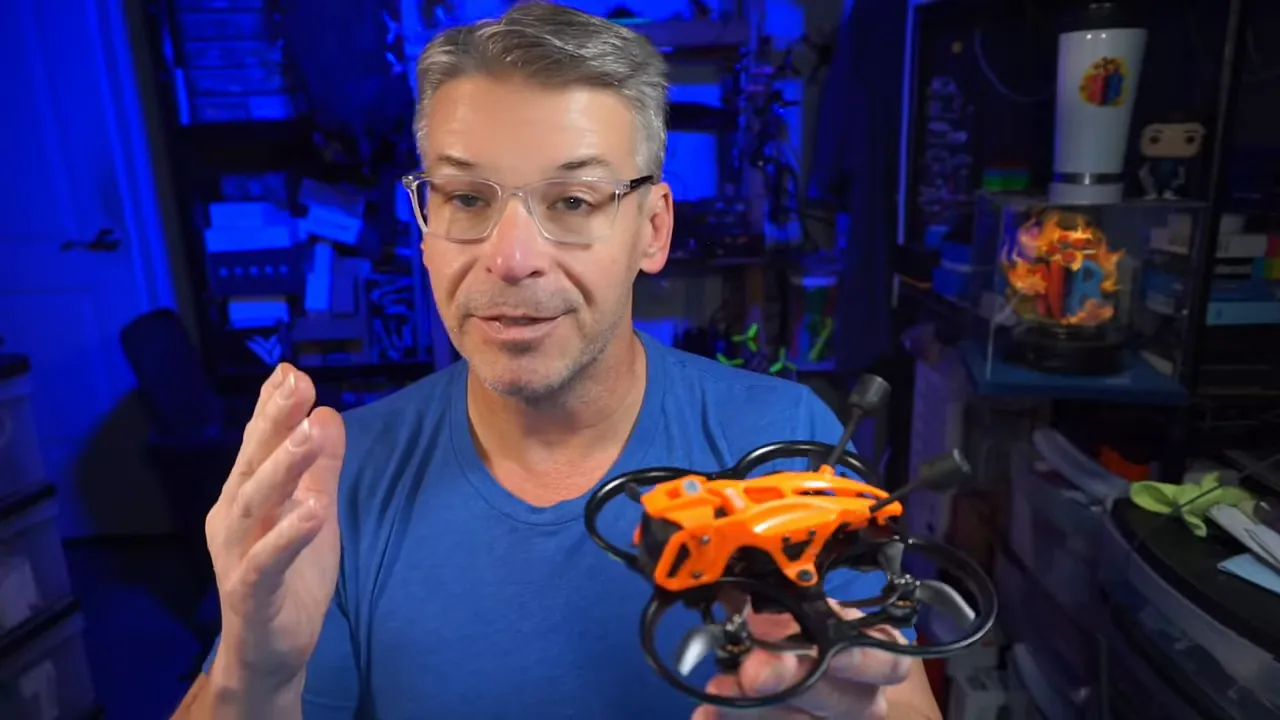 Hand holding a DarkStar22 micro whoop with orange floating canopy and ducted props, clearly showing canopy fitment