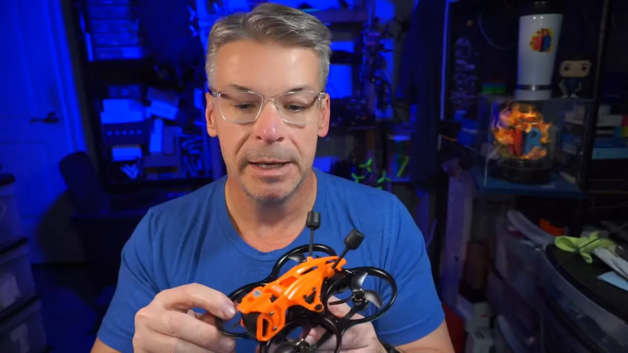 Person holding a DarkStar22 micro whoop with orange floating canopy and dual antennas with a clear view of the drone