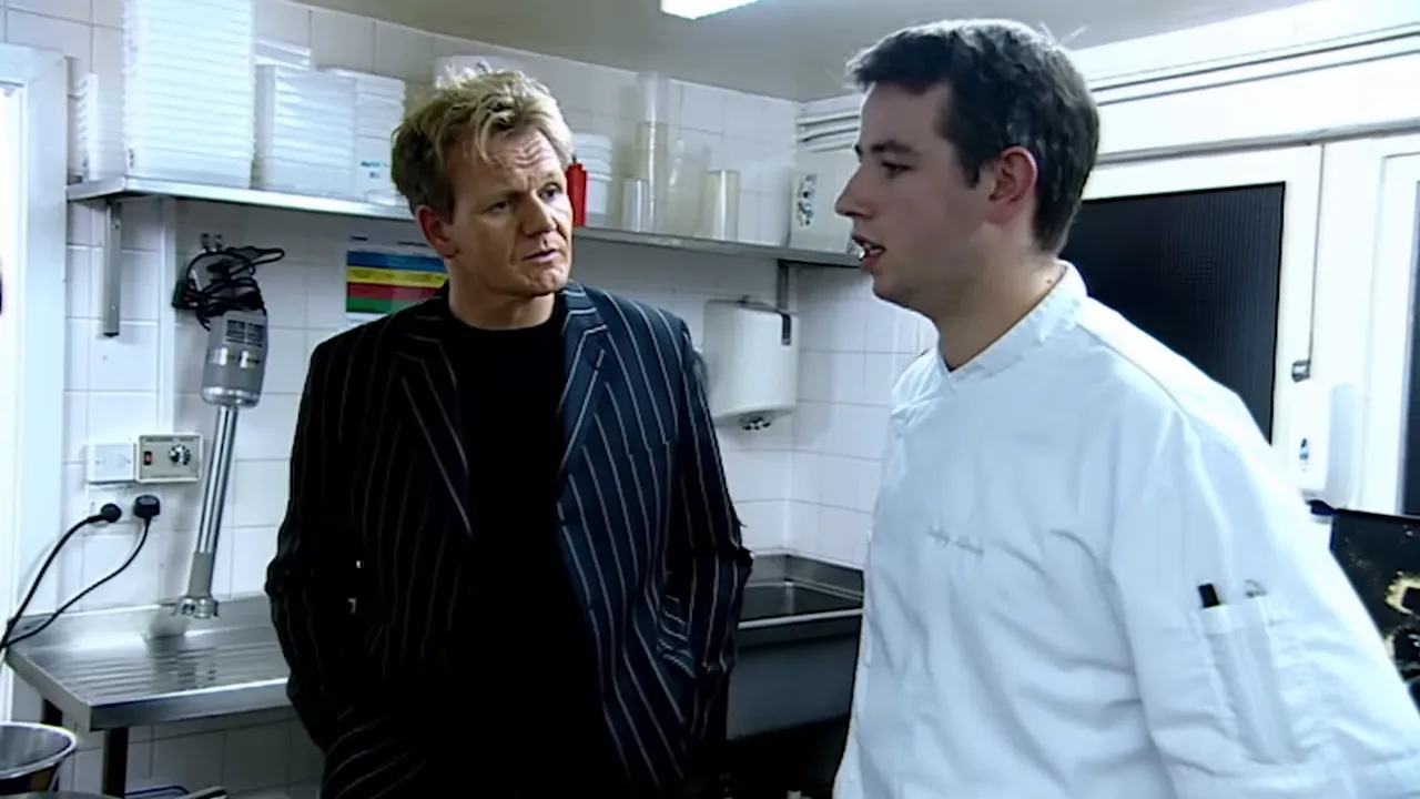 Two chefs in discussion in a restaurant kitchen next to prep counters